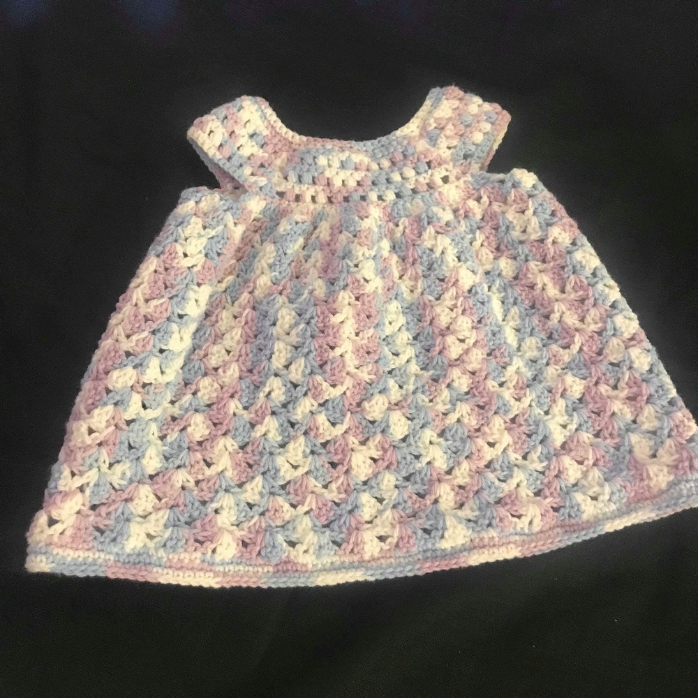 A handmade crocheted multi-color baby dress.